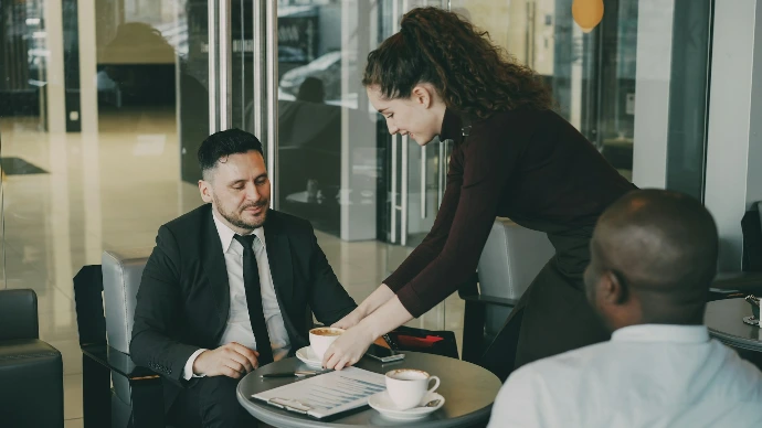Waitress serving coffee to two businessmen in cafe. 